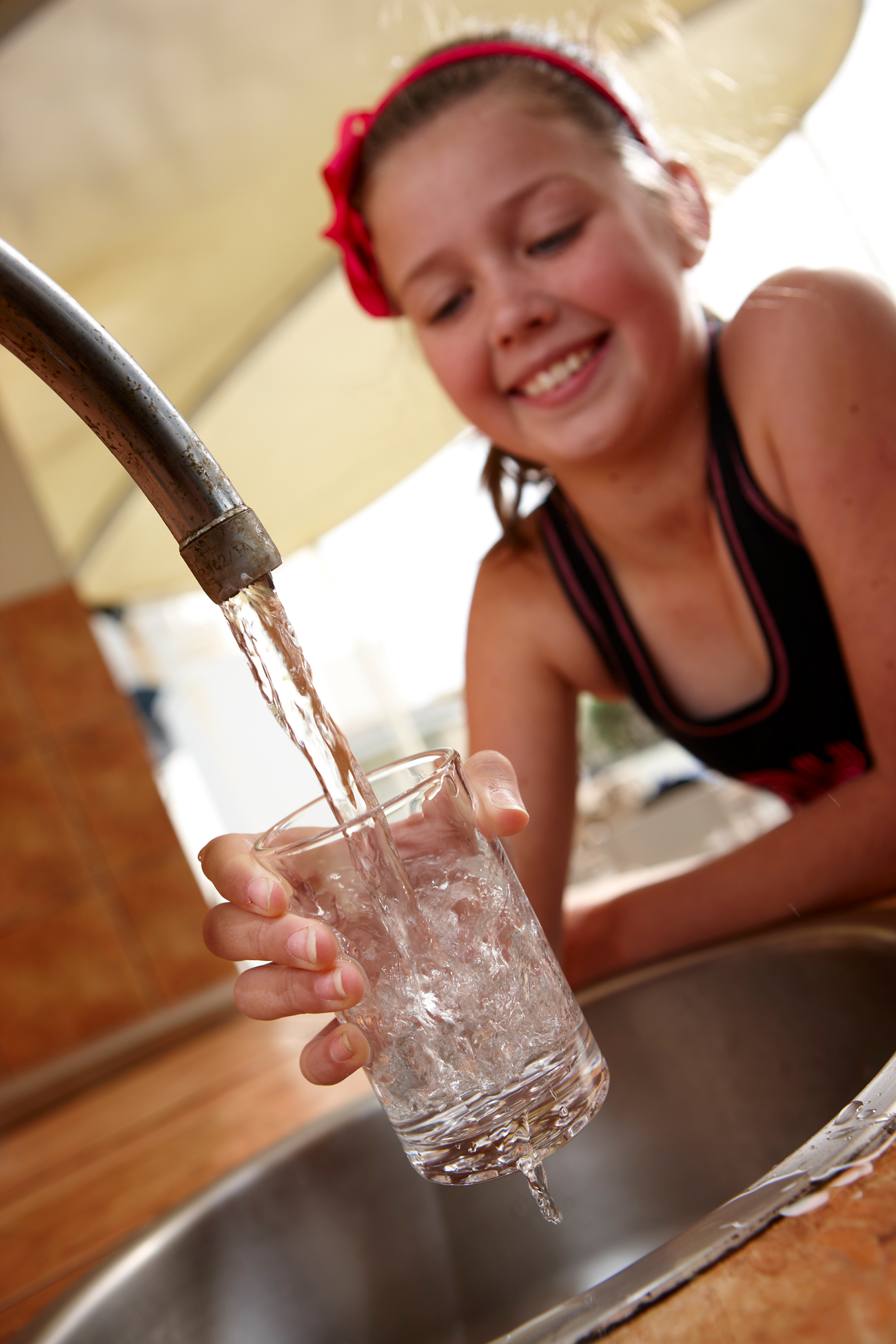 Girl filling glass of water from tap